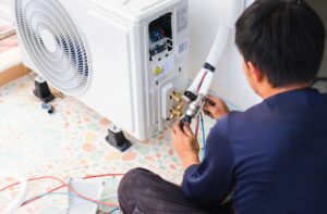 Technician working on an outdoor air conditioning unit.