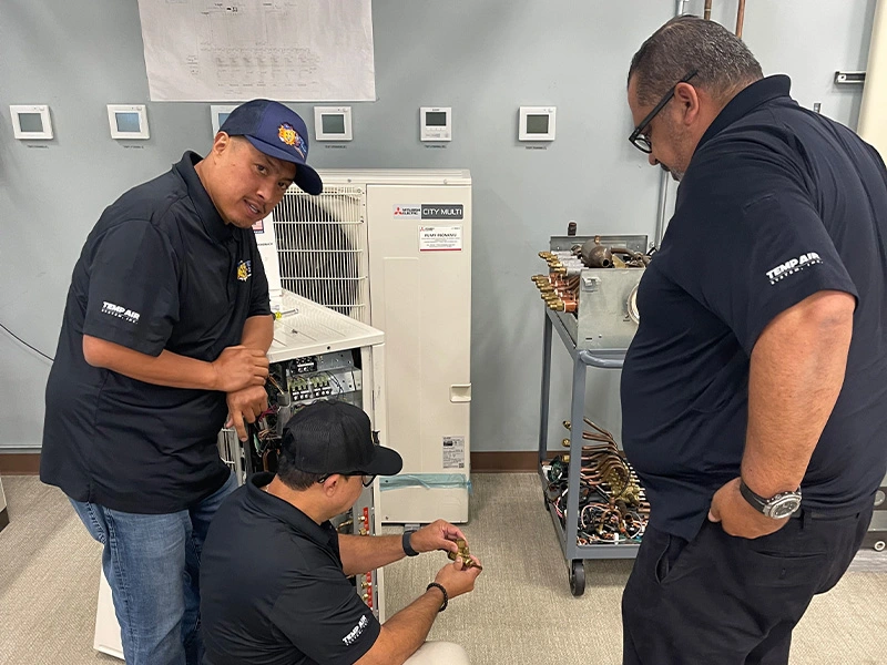 Technicians working on a Mitsubishi HVAC unit.